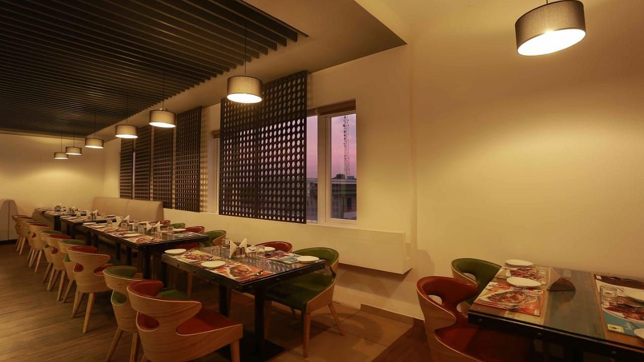 Mint N Mustard Restaurant at Mayberry Tiruppur with tables and chairs arranged neatly with hanging lights overhead
